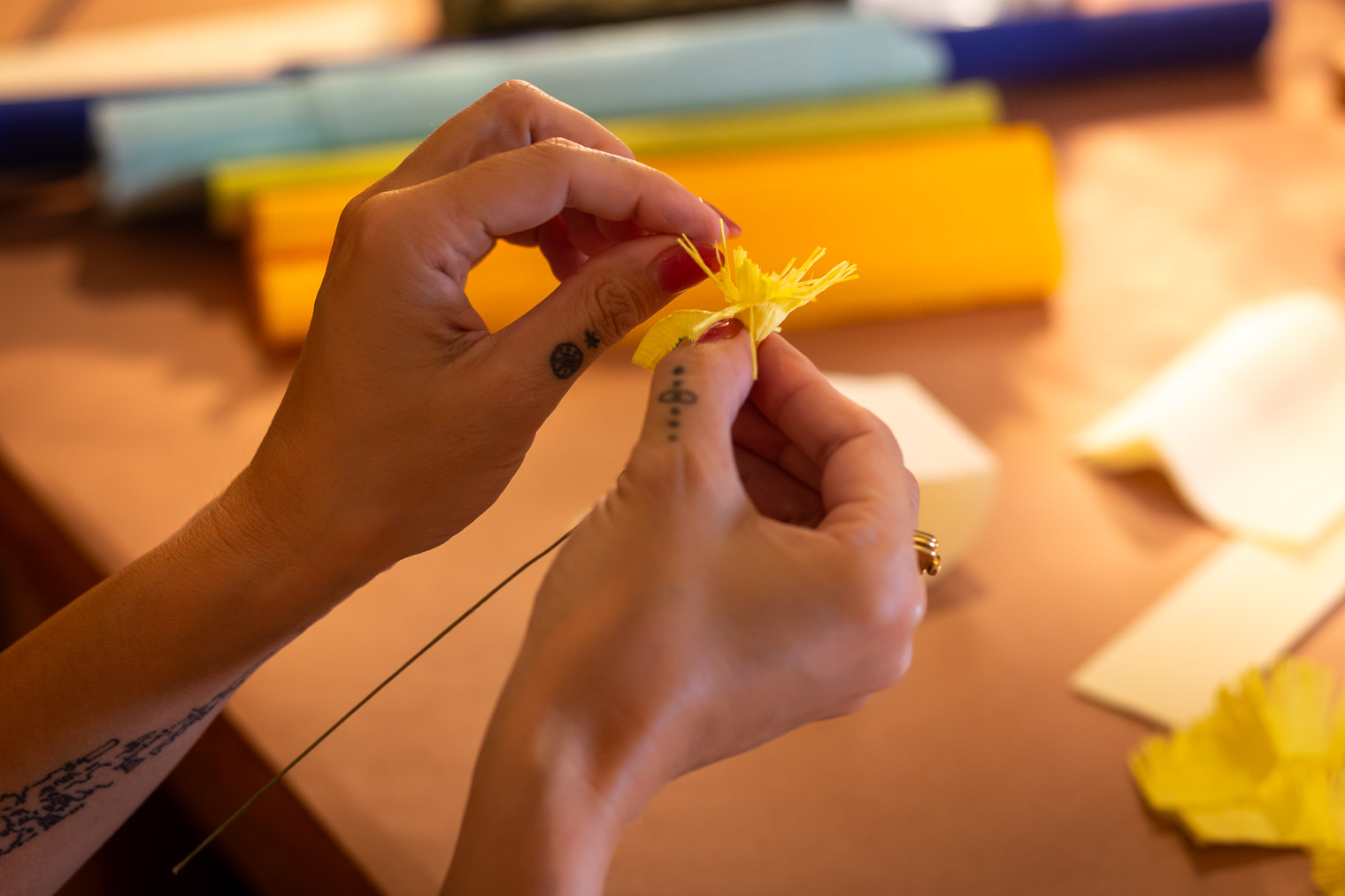 Hands shaping a paper flower petal